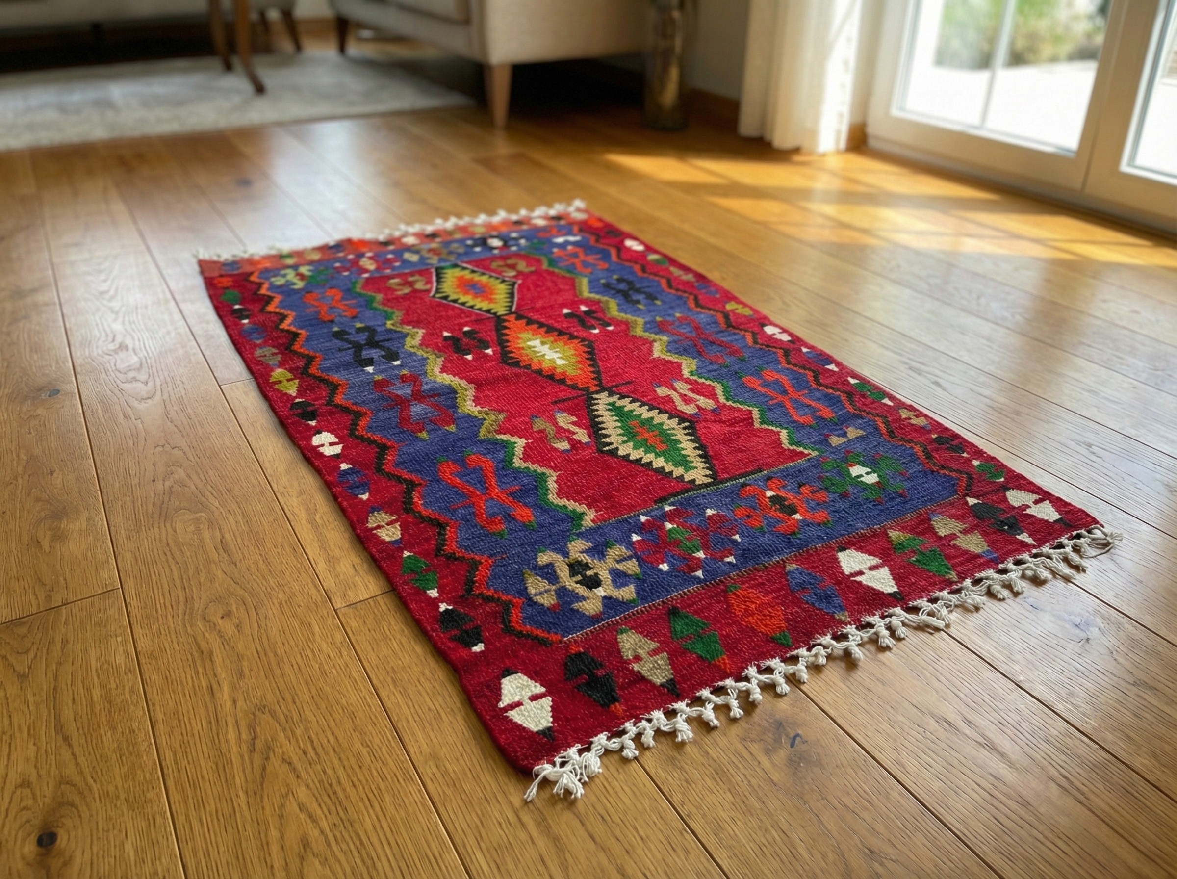 Vintage handwoven Turkish Afyon kilim rug featuring a bold red central field with three large geometric diamond medallions. The dark blue borders contain the traditional "Saç Bağı" (hair ornament) bridal motifs. Colorful accents in green, orange, and white.