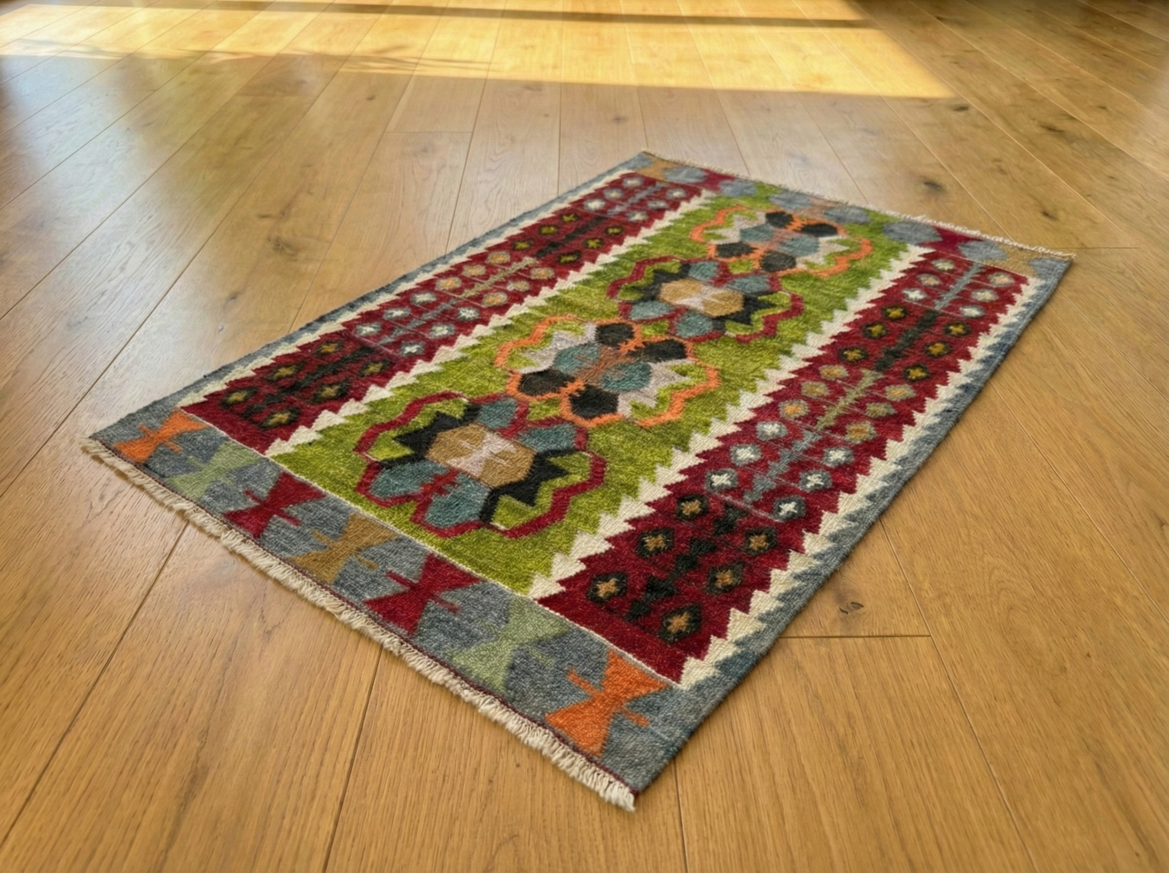 Vintage handwoven Turkish Eşme kilim rug with a bright green center field featuring geometric medallions and deep red borders. Small boho area rug or wall hanging in green, red, and blue wool.